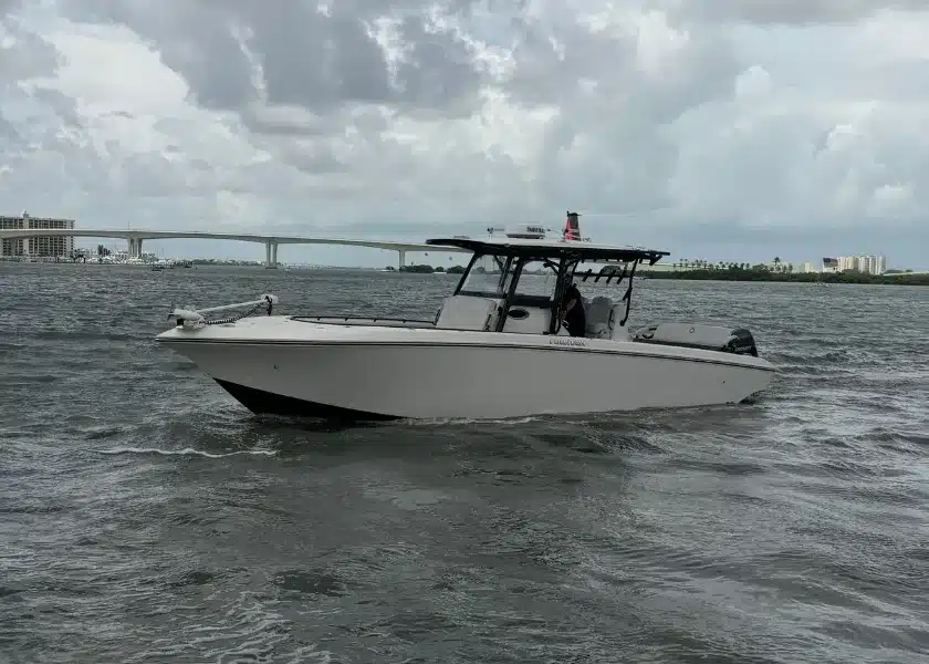 A center console sport fishing boat underway on a Tampa Bay channel with a bridge behind it