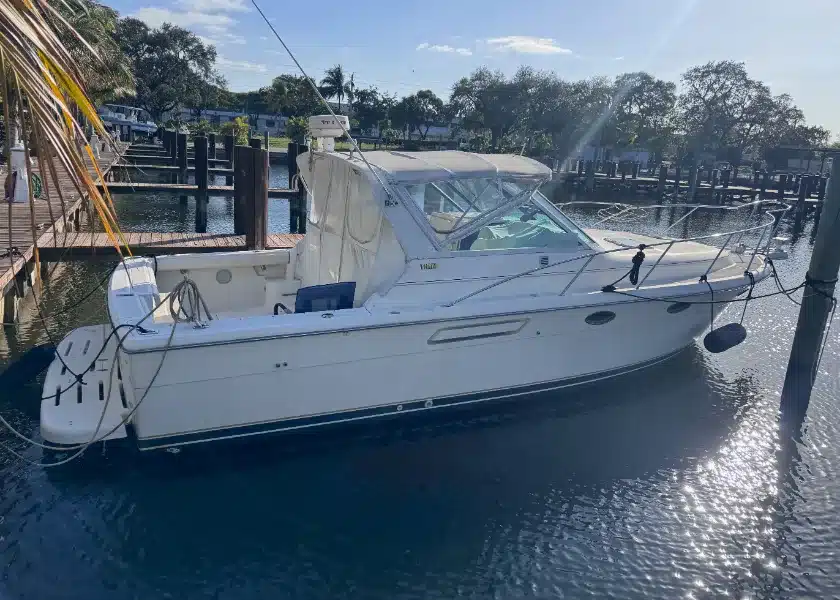A cream express cruiser with a canvas enclosure tied at a wooden dock