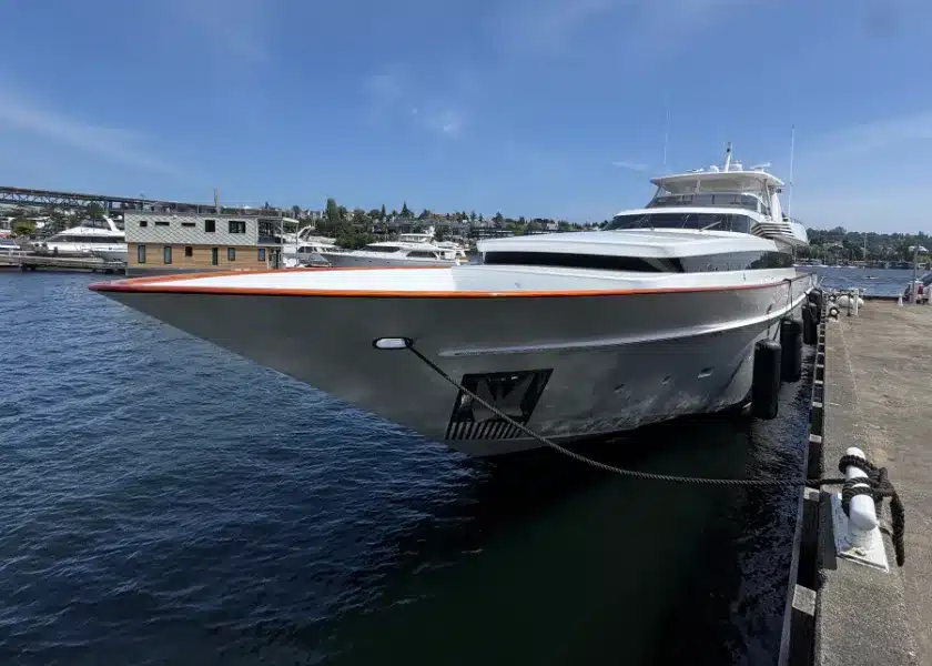 A large motor yacht tied at a Seattle dock with the city shoreline behind it