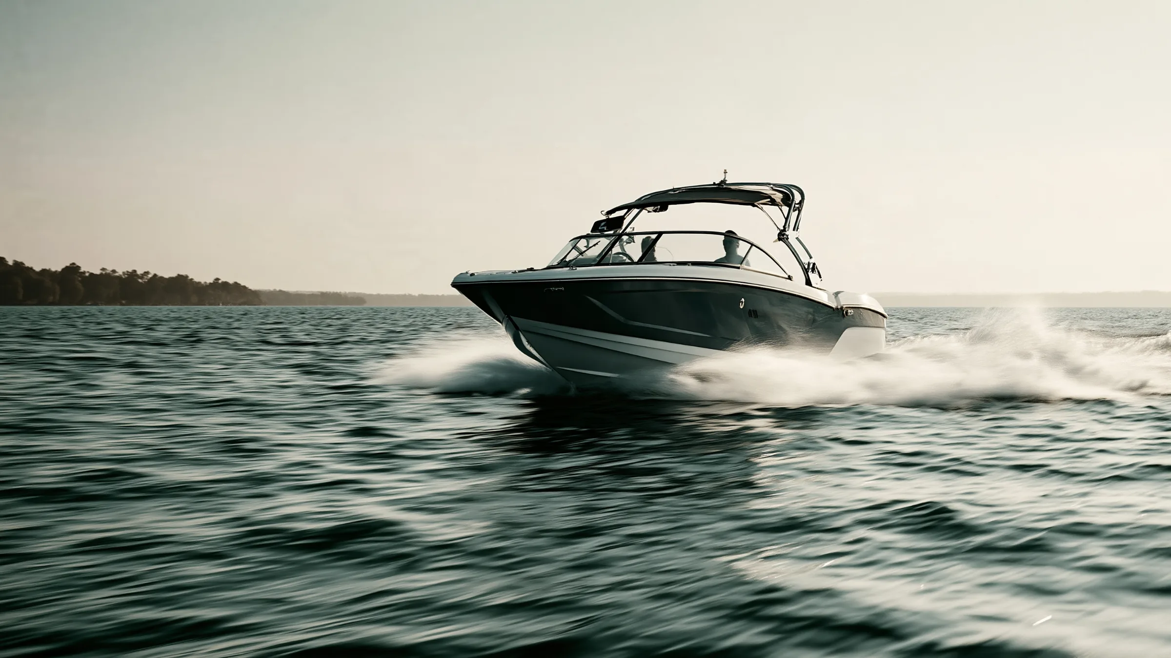 A white and navy bowrider running at moderate speed across open lake water with a soft bow spray
