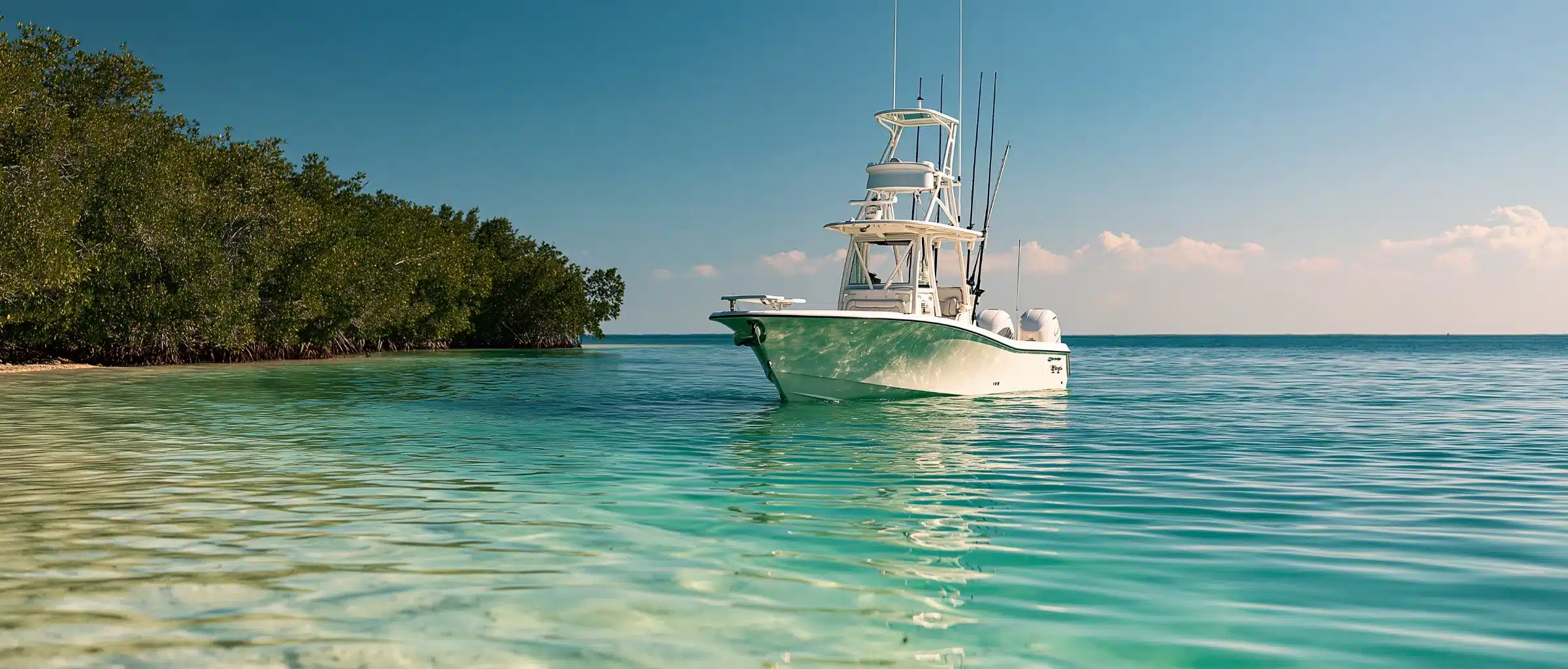 A center console fishing boat with a tower and twin outboards on clear turquoise shallows beside a mangrove island in Florida
