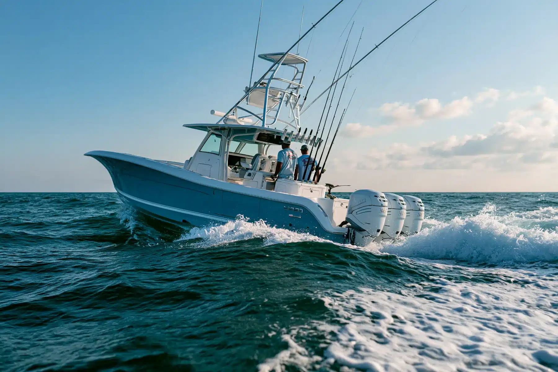 An offshore center console with a tower and triple outboards running through open ocean swells