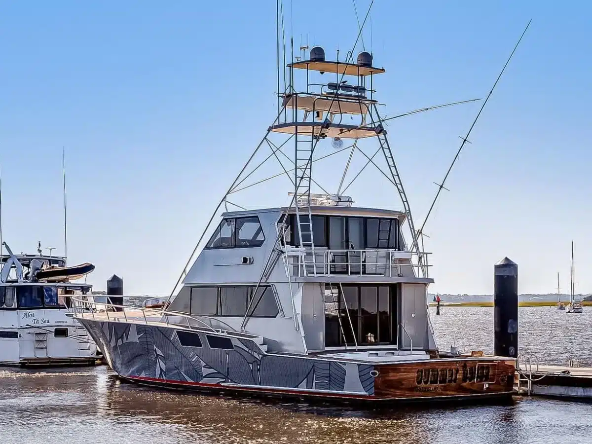 A convertible sportfisher with a tall tuna tower and outriggers tied at a marina dock on a clear morning