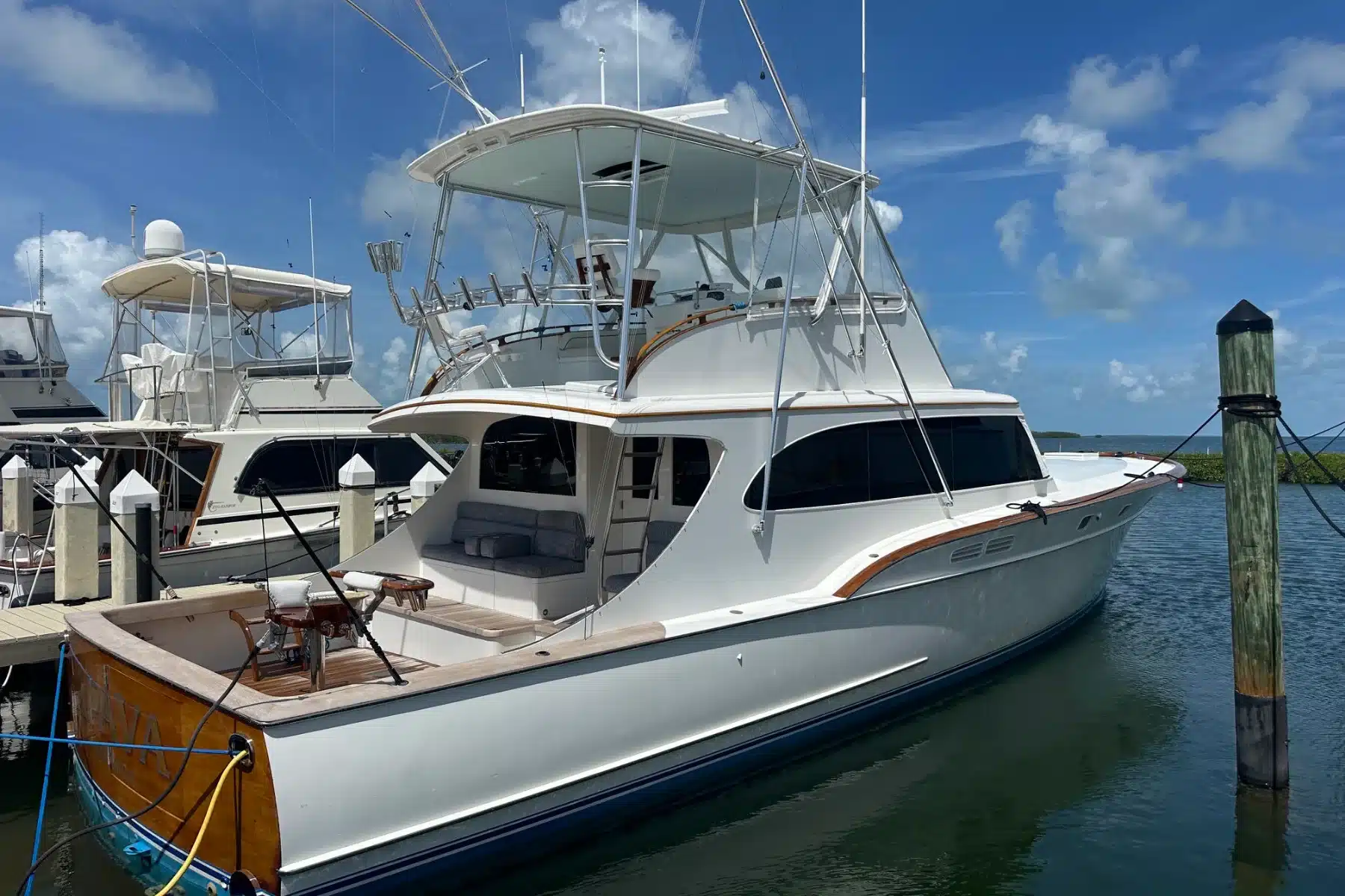A white Rybovich convertible sportfisher with a varnished teak transom, fighting chair and tuna tower, tied stern-in at a Florida Keys dock