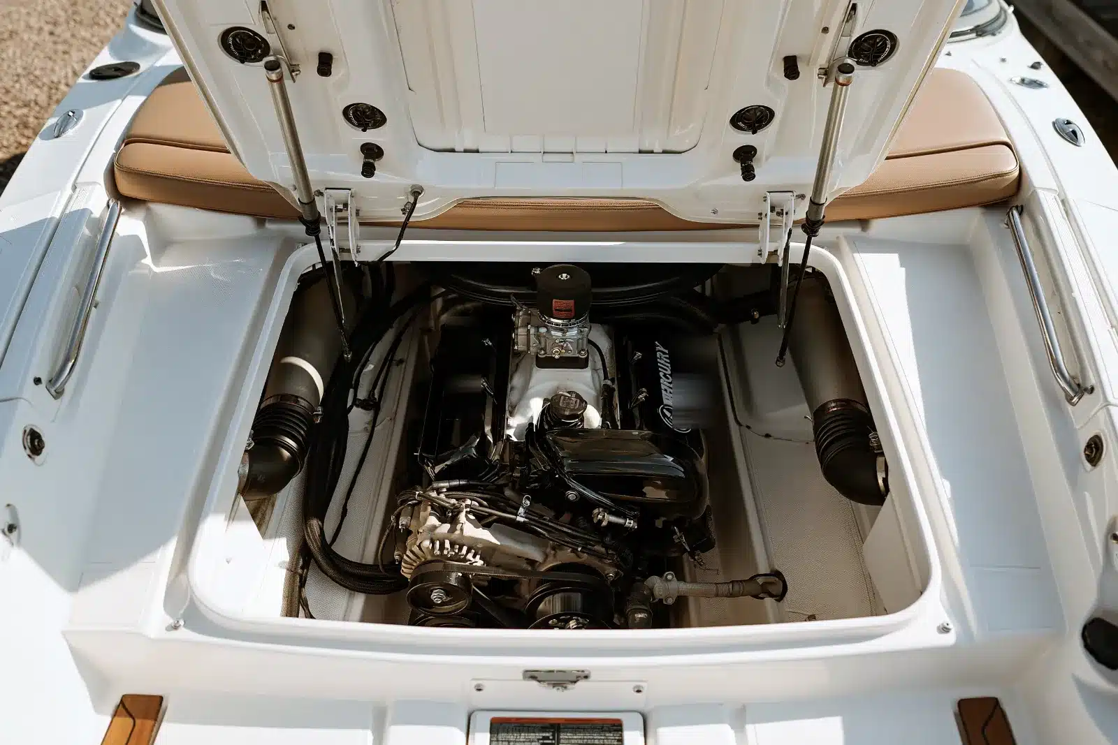 Looking down into the open engine hatch of a white bowrider at a black V8 sterndrive engine sitting in a clean fiberglass bilge